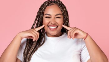 Body Positive. Happy African American Obese Lady Touching Cheeks Posing Smiling To Camera Over Pink Studio Background. Female Beauty And Self Confidence Concept