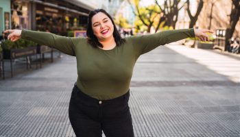 Portrait of young plus size woman smiling while standing outdoors at the street. Urban concept.