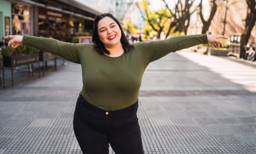 Portrait of young plus size woman smiling while standing outdoors at the street. Urban concept.