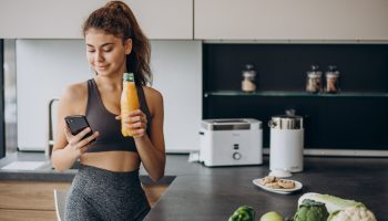 Sporty woman at kitchen using mobile phone
